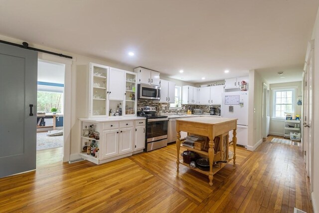 155 Great Marsh Rd, Barnstable, MA 02632 - kitchen with stainless steel appliances, open shelves, light wood-style floors, light countertops, and white cabinetry