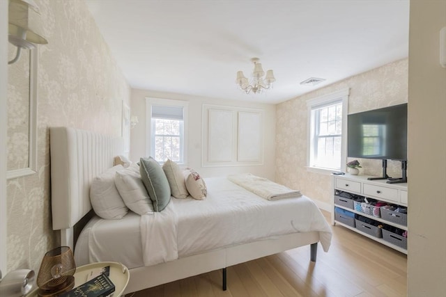 155 Great Marsh Rd, Barnstable, MA 02632 - bedroom with wallpapered walls, multiple windows, light wood-style flooring, and a chandelier