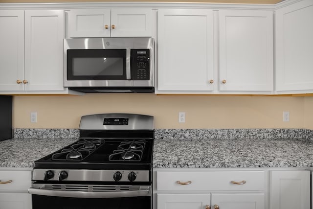 kitchen with white cabinetry, light stone counters, and stainless steel appliances