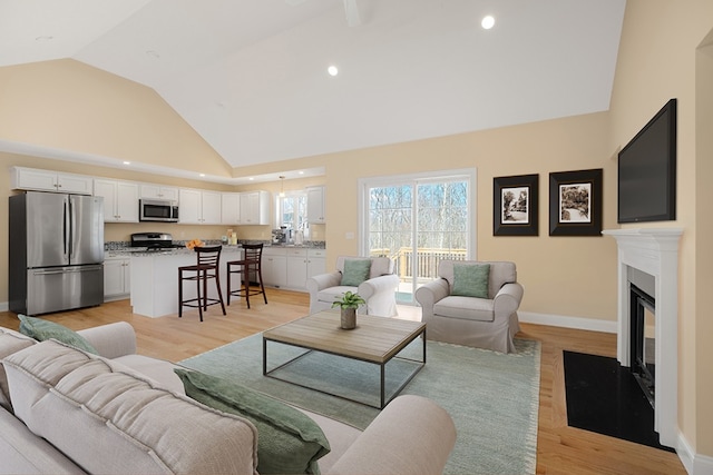 living room with high vaulted ceiling and light hardwood / wood-style floors