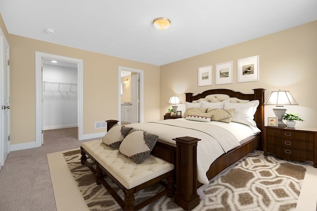 carpeted bedroom with a spacious closet, ensuite bathroom, and a closet