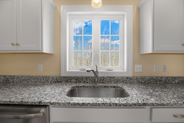 kitchen with white cabinets, light stone countertops, and dishwasher