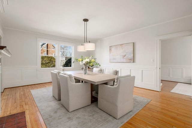 unfurnished dining area featuring ornamental molding, light wood finished floors, and a decorative wall