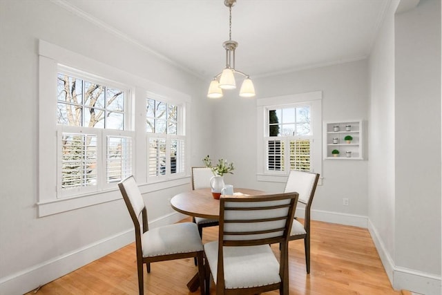 dining area featuring light wood-style floors, crown molding, baseboards, and a wealth of natural light