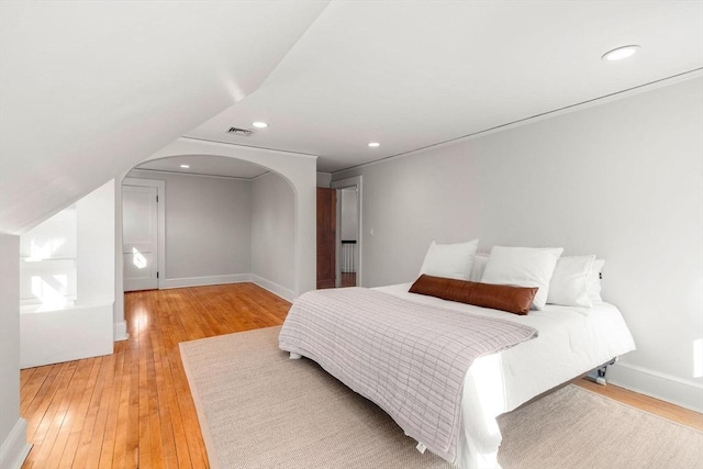 bedroom with arched walkways, recessed lighting, visible vents, light wood-style floors, and baseboards