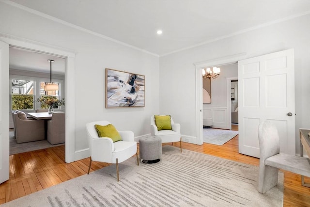 sitting room with a notable chandelier, recessed lighting, baseboards, hardwood / wood-style floors, and crown molding