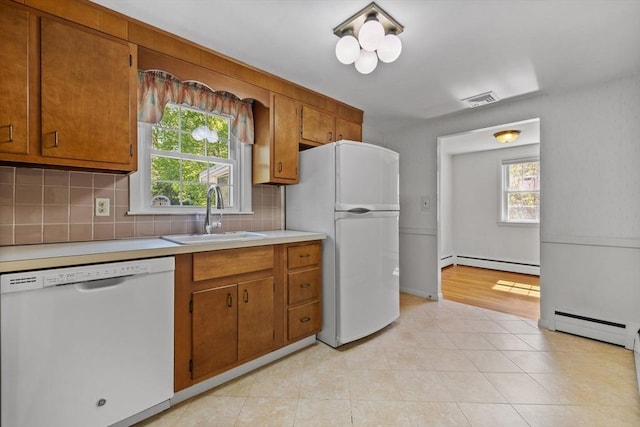 kitchen with white appliances, a sink, a baseboard heating unit, and light countertops