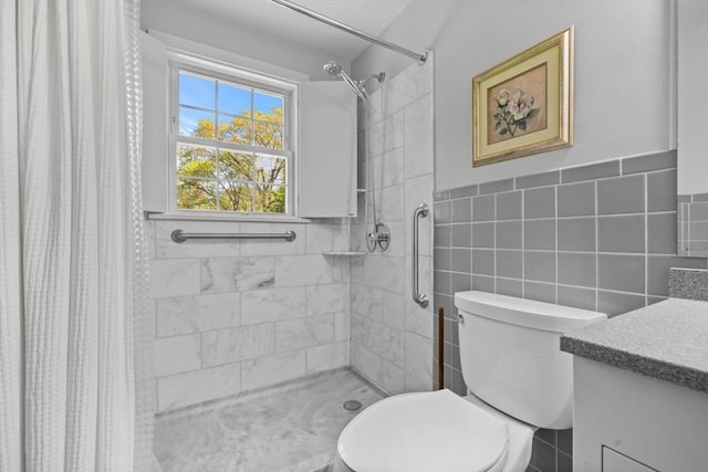 full bath featuring tiled shower, toilet, tile walls, and vanity