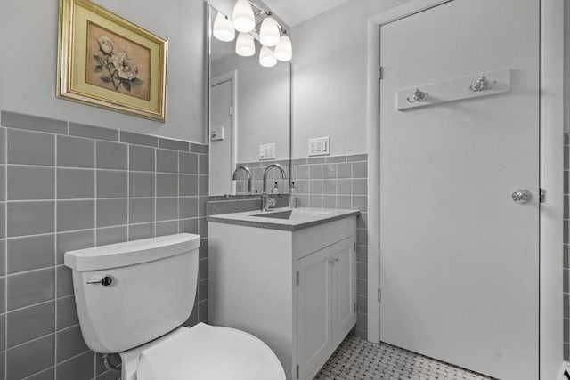 bathroom with tile walls, toilet, wainscoting, and vanity