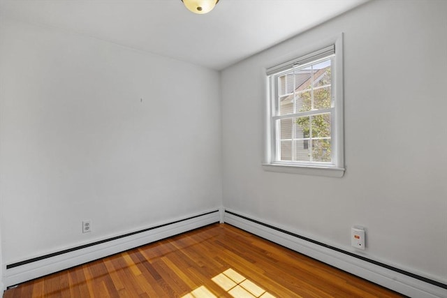 unfurnished room featuring baseboard heating and wood finished floors