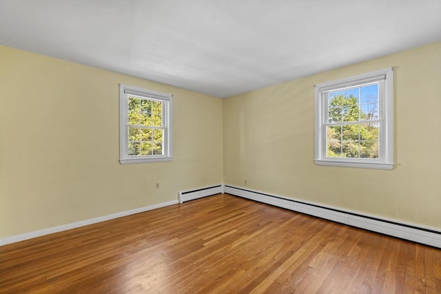 spare room featuring plenty of natural light, hardwood / wood-style floors, a baseboard radiator, and baseboards