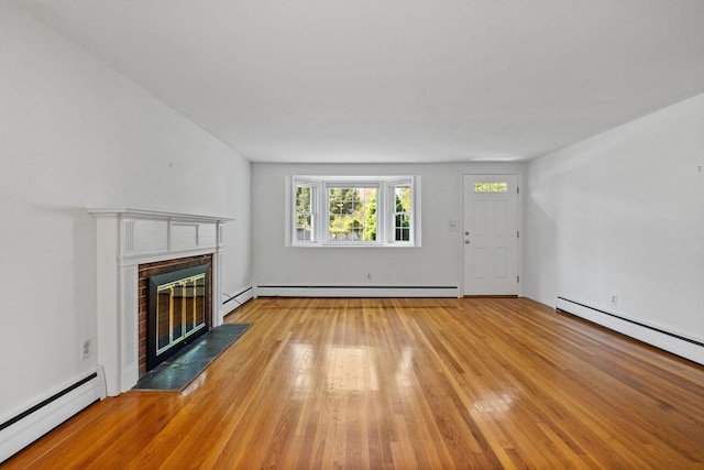 unfurnished living room with a baseboard heating unit, a fireplace, wood finished floors, and a baseboard radiator
