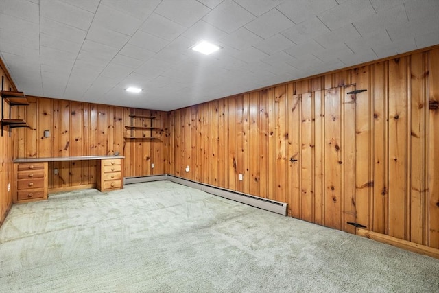 finished below grade area featuring light carpet, wooden walls, and baseboard heating