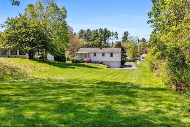 view of green lawn featuring a garage and driveway