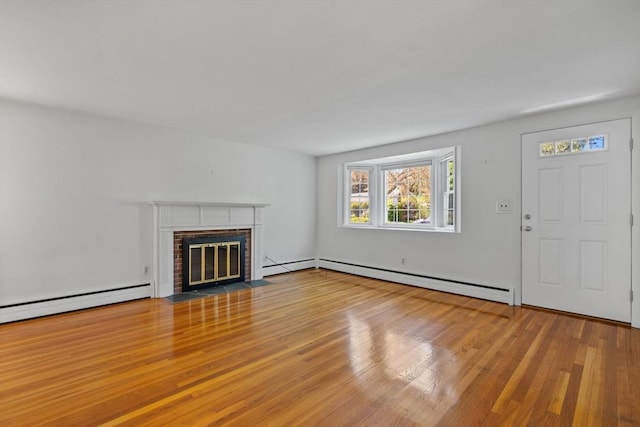 unfurnished living room featuring a baseboard heating unit, wood finished floors, a brick fireplace, and baseboard heating