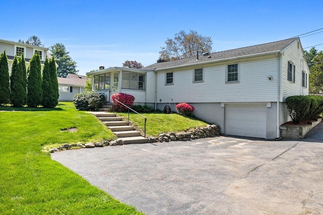 view of front facade with a garage, a sunroom, a front yard, and driveway