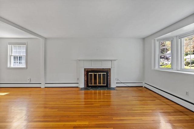 unfurnished living room with a baseboard heating unit, wood finished floors, and a brick fireplace