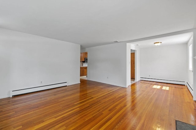 unfurnished living room with a baseboard heating unit and wood-type flooring