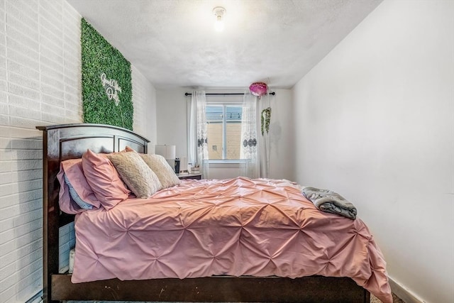 bedroom with a textured ceiling and brick wall