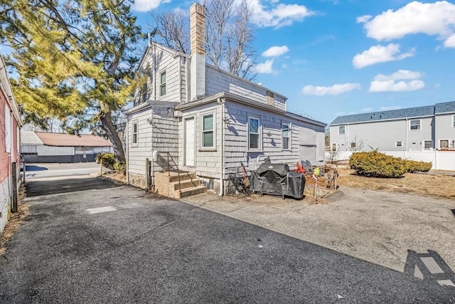 view of side of property featuring fence and a chimney