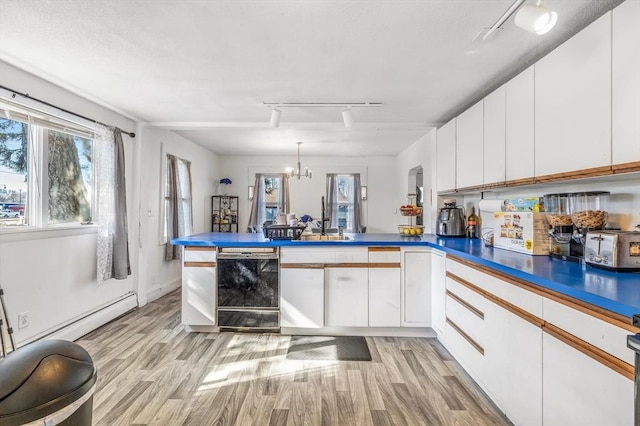 kitchen featuring white cabinetry, a peninsula, and light wood-type flooring