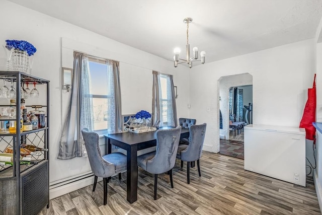 dining space with an inviting chandelier, wood finished floors, arched walkways, and a baseboard radiator