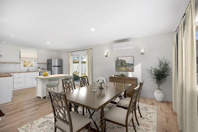 dining room with light hardwood / wood-style flooring, plenty of natural light, and a wall mounted AC