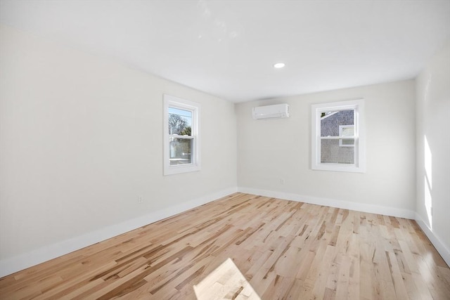 unfurnished room featuring light wood-type flooring and an AC wall unit