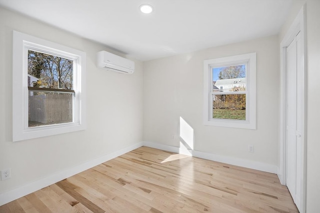 unfurnished room with light wood-type flooring and a wall unit AC