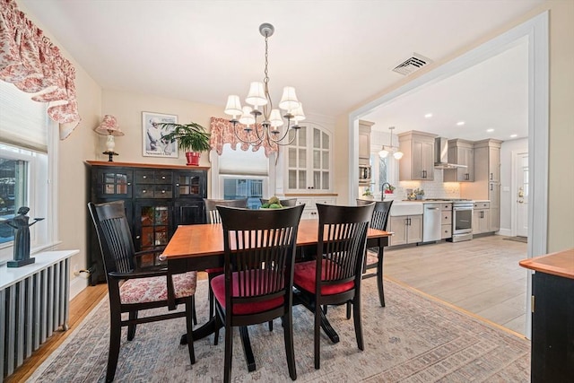 dining room with plenty of natural light, sink, an inviting chandelier, and light wood-type flooring