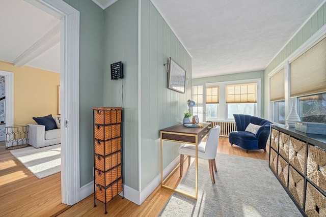 interior space featuring crown molding, wooden walls, radiator, and light hardwood / wood-style floors