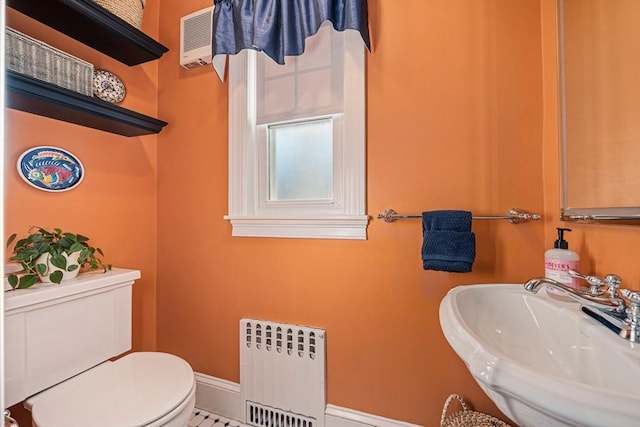 bathroom with tile patterned floors, radiator heating unit, toilet, and sink