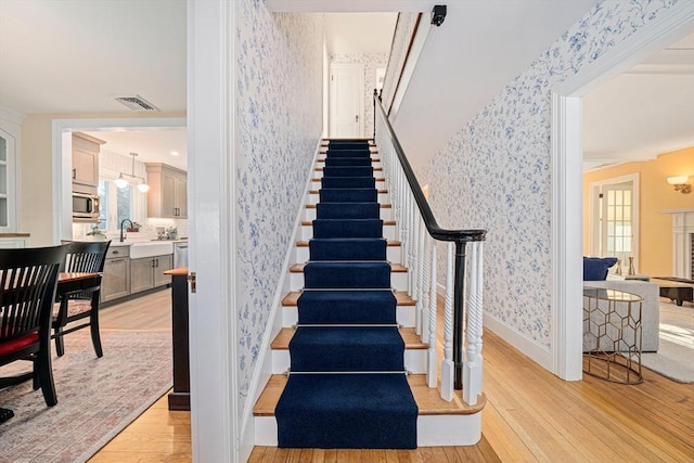 staircase featuring sink and hardwood / wood-style floors