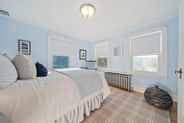 bedroom with radiator heating unit and wood-type flooring