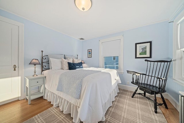 bedroom featuring multiple windows, wood-type flooring, and crown molding