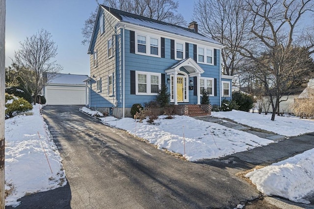 colonial inspired home with a garage and an outbuilding