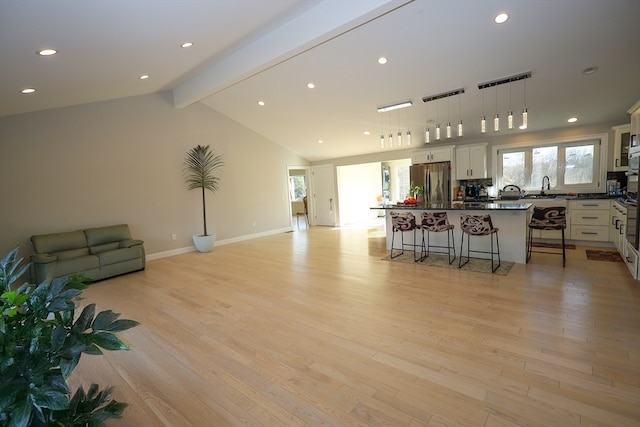 kitchen with a kitchen breakfast bar, a kitchen island, light hardwood / wood-style flooring, white cabinetry, and stainless steel refrigerator