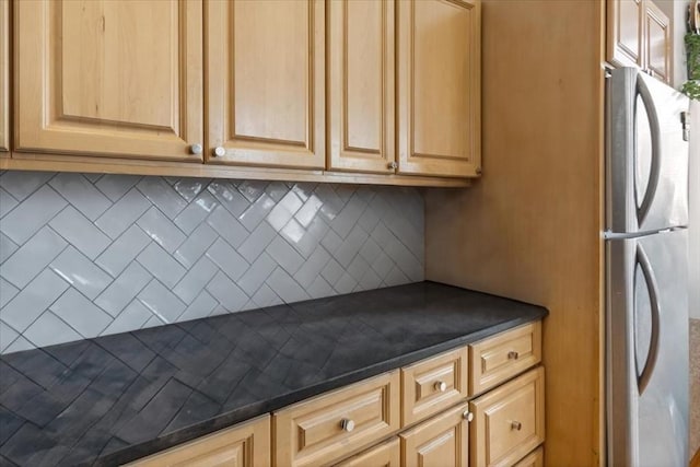 kitchen featuring freestanding refrigerator, dark countertops, decorative backsplash, and light brown cabinetry