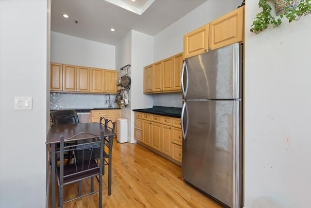 kitchen with appliances with stainless steel finishes, tasteful backsplash, light wood-style floors, light brown cabinets, and recessed lighting