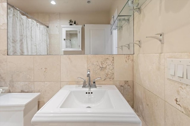 bathroom with tile walls, a sink, a shower with shower curtain, and recessed lighting