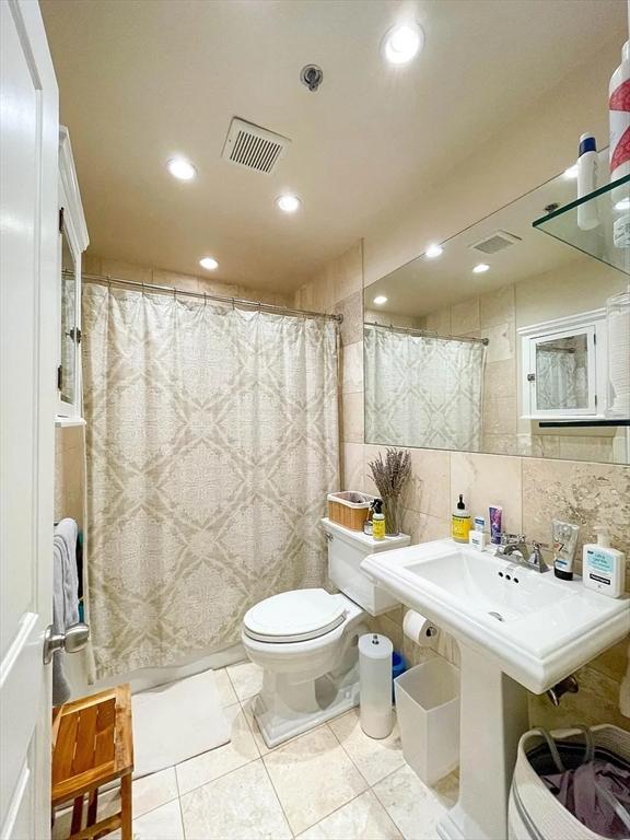 bathroom featuring toilet, tile walls, recessed lighting, curtained shower, and decorative backsplash