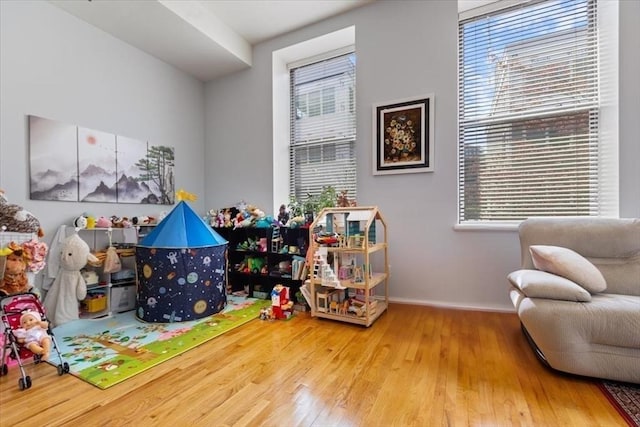 recreation room featuring wood finished floors, healthy amount of natural light, and baseboards