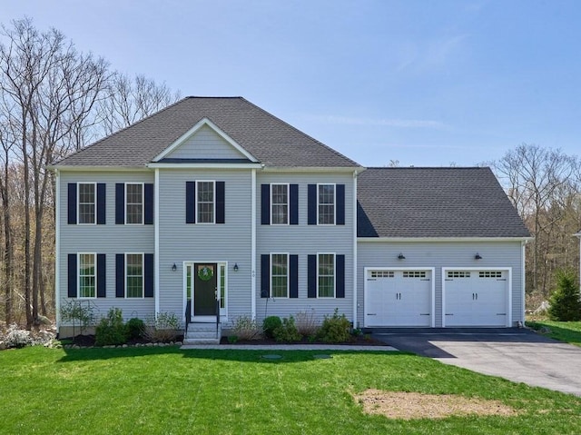 colonial home featuring aphalt driveway, a front lawn, roof with shingles, and a garage