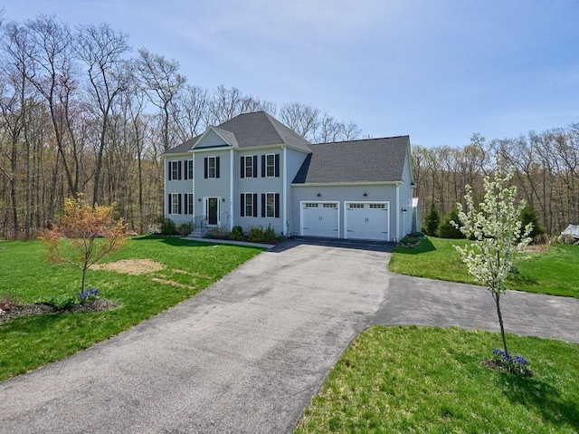colonial inspired home featuring a garage, a front yard, and aphalt driveway