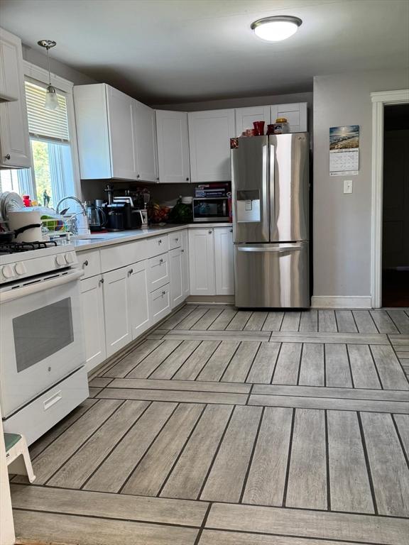335 Euclid Ave, Lynn, MA 01904 - kitchen featuring stainless steel fridge with ice dispenser, gas range gas stove, light wood-type flooring, white cabinets, and a sink