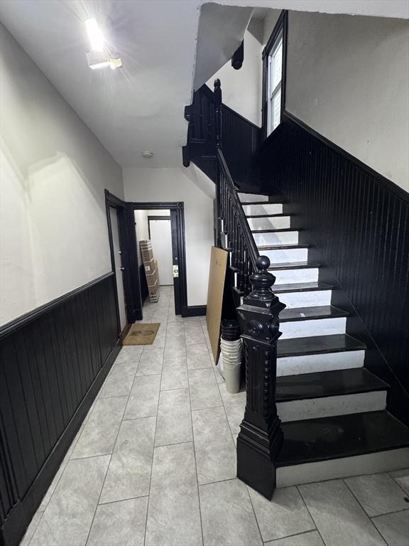 132 Chelsea St, Boston, MA 02128 - stairway with a wainscoted wall and tile patterned floors