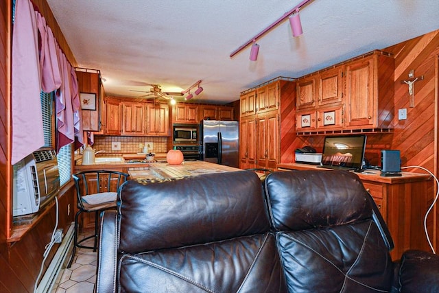 living room featuring track lighting, wood walls, a desk, and a ceiling fan