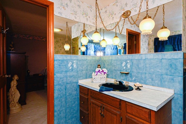 bathroom featuring wallpapered walls, tile walls, vanity, and a wainscoted wall