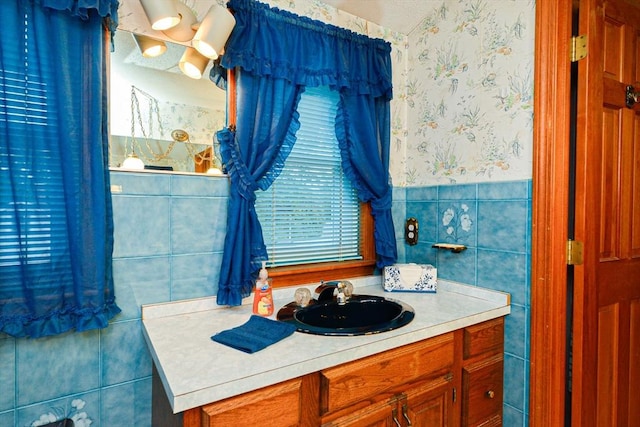 bathroom featuring wallpapered walls, tile walls, wainscoting, and vanity