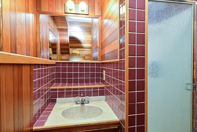 bathroom featuring vanity, wood walls, decorative backsplash, and an enclosed shower